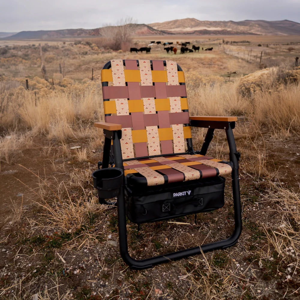 PARKIT Folding chair with a patterned seat in a ranch landscape with mountains and grazing cattle.